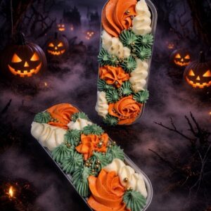 Two decorative dessert boxes with orange, green, and white frosting in a Halloween scene with pumpkins and a full moon behind bats.
